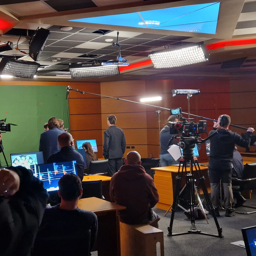 Professional production sound services in Italy, featuring a location sound crew and boom operator holding a microphone boom pole on a film and television studio set.